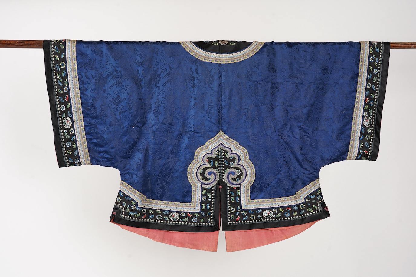 A late 19th century Chinese blue silk damask jacket, woven with Phoenix and auspicious symbols. The jacket edged with ornate rows of braiding and silk embroidery, the interior with original pink silk lining. The jacket f